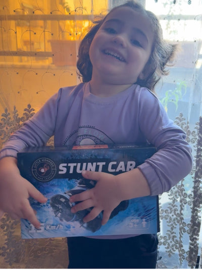 Vrolijk meisje knuffelt doos met stunt RC auto voor kinderen terwijl ze blij in kamer staat Race Auto