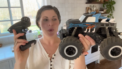 Vrouw toont enthousiaste grote RC monstertruck met afstandsbediening in lichtkeuken Race Auto