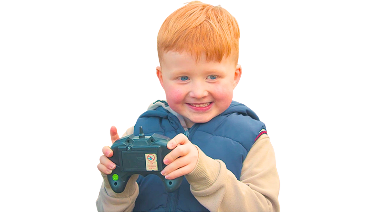Jongentje met een afstandsbediening lacht terwijl hij een RC auto bestuurt Race Auto.